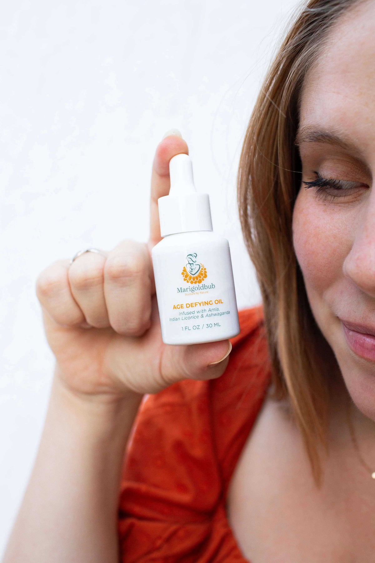 Age Defying Face Oil in a white glass dropper bottle with a colorful label and orange-red text