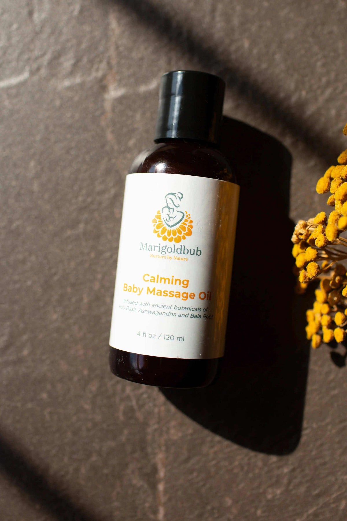 Calming Baby Massage Oil in an amber bottle with a black cap and white label featuring yellow and teal branding