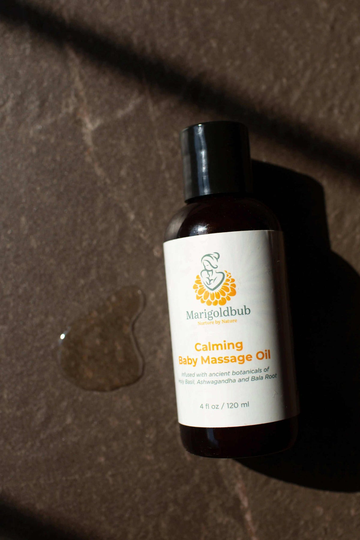 Calming Baby Massage Oil in a dark amber bottle with a black cap and white label featuring a yellow floral logo