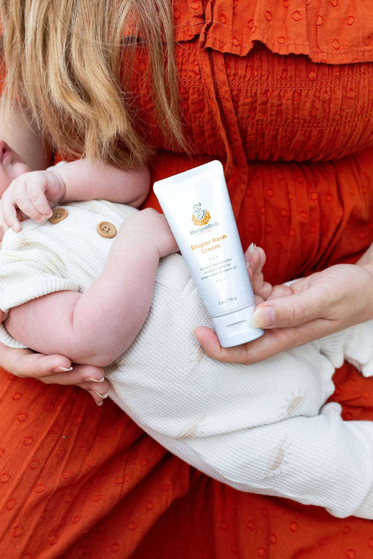 Diaper Rash Cream in a white squeeze tube with orange and gold label, held beside a baby in a white outfit