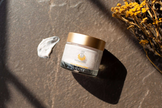 Marigoldbub's Vital Moisturizer in a clear jar with a gold lid, showing pale cream moisturizer and a botanical label.